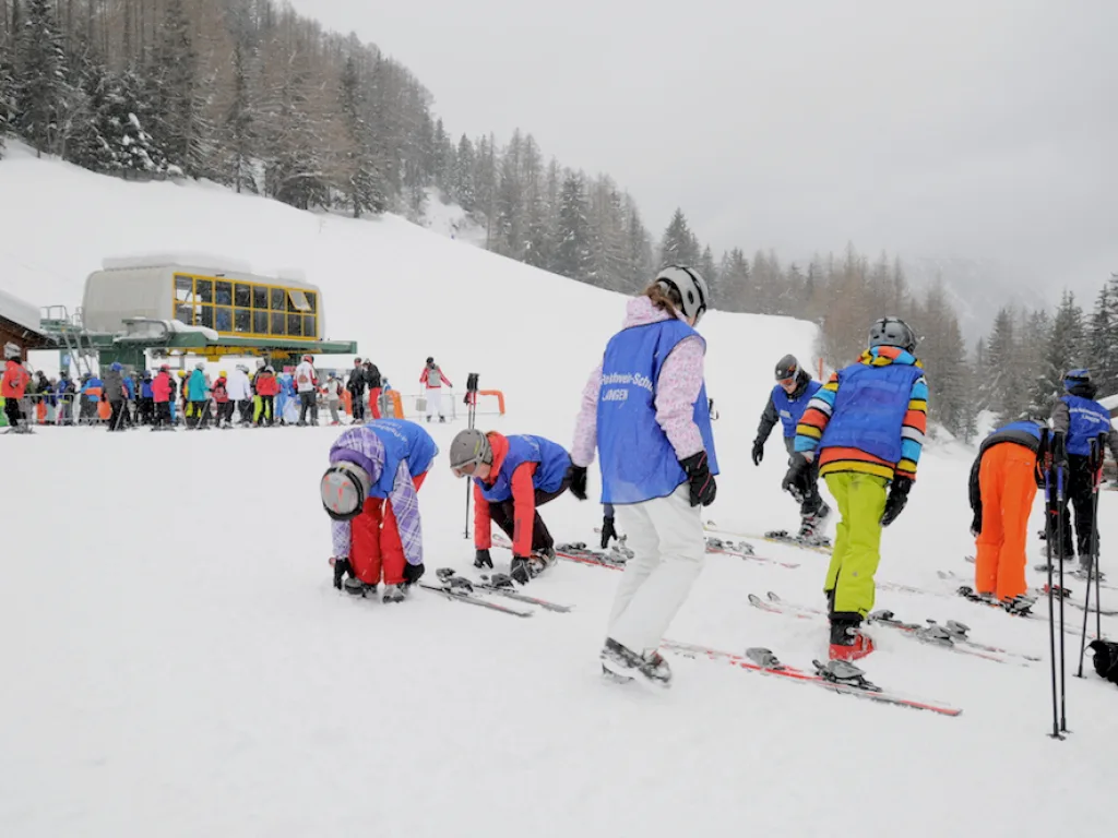 Jugendliche rüsten sich an der Talstation für die Piste.